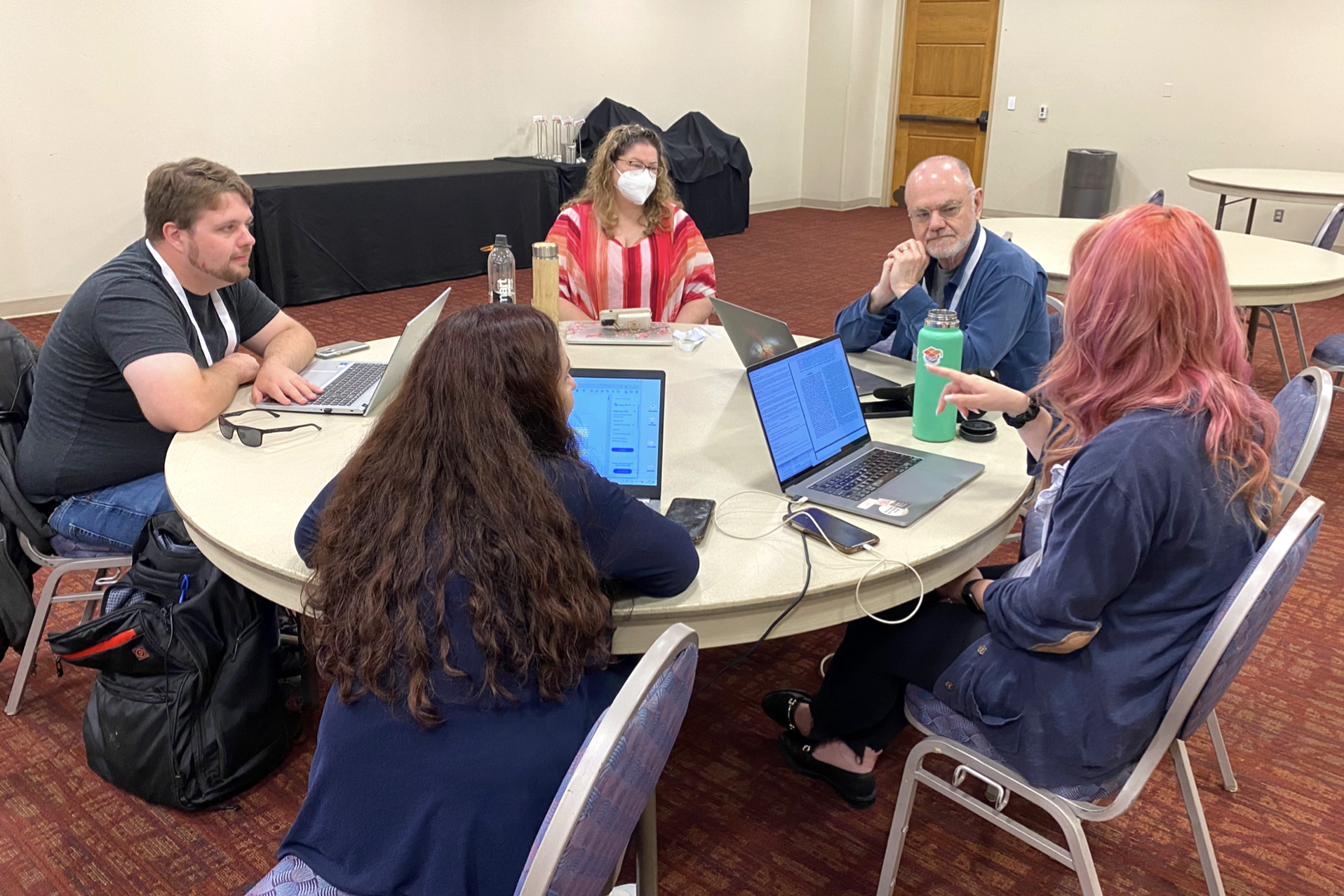 A group of people sits around a table discussing a peer review example.